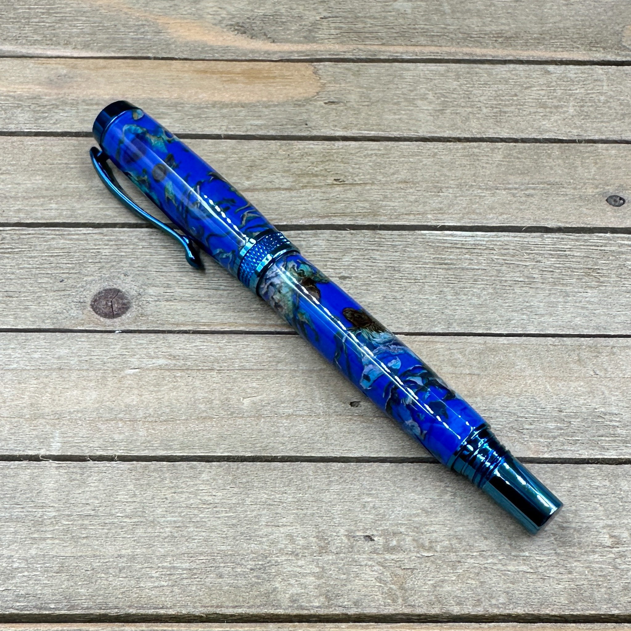 Blue titanium rollerball pen made with cast flowers in clear blue resin  Blue titanium rollerball pen made with cast flowers in clear blue resin